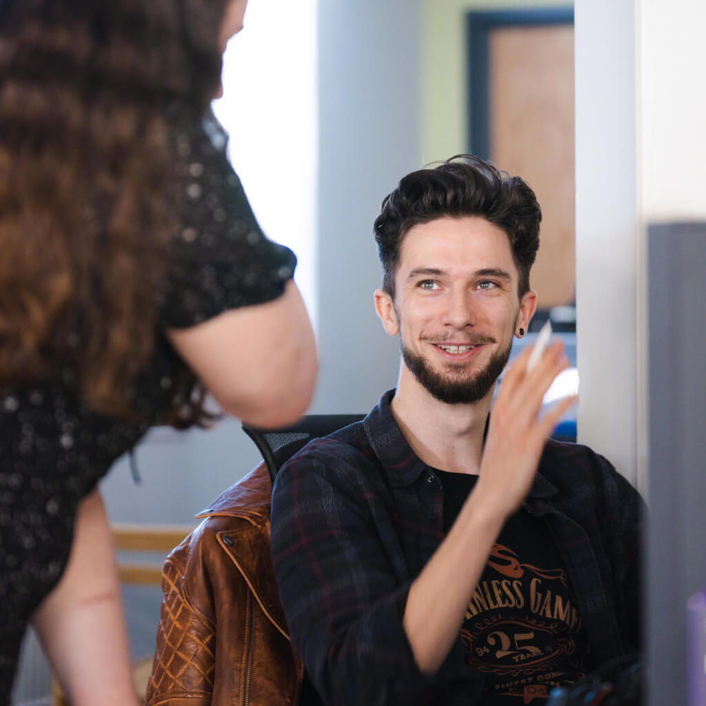 A photo of a Stainless Games team member smiling while talking to another